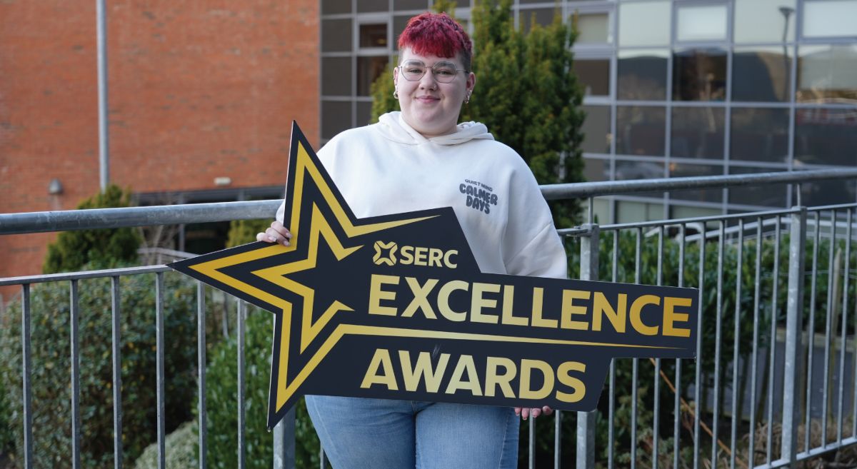 Image showing student holding Excellence Awards logo prop outside